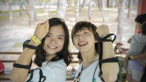 Two smiling women raise their arms to show their wristbands