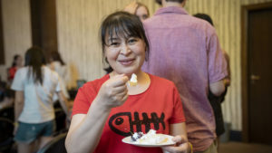 A smiling woman eats a piece of cake at a party