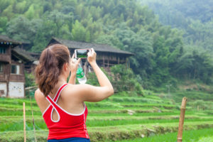 A woman photographs a rural village and green terraced fields