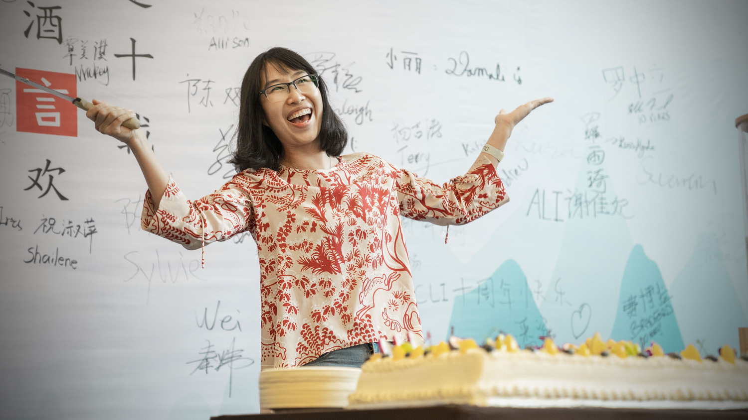 A Chinese woman smiling in front of a classroom