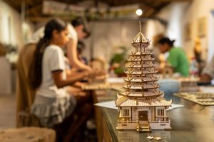 A finished wooden pagoda model stands on a table in a craft workshop