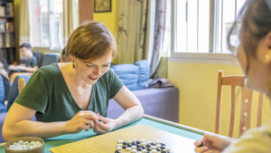 A woman leans over a table to play Go