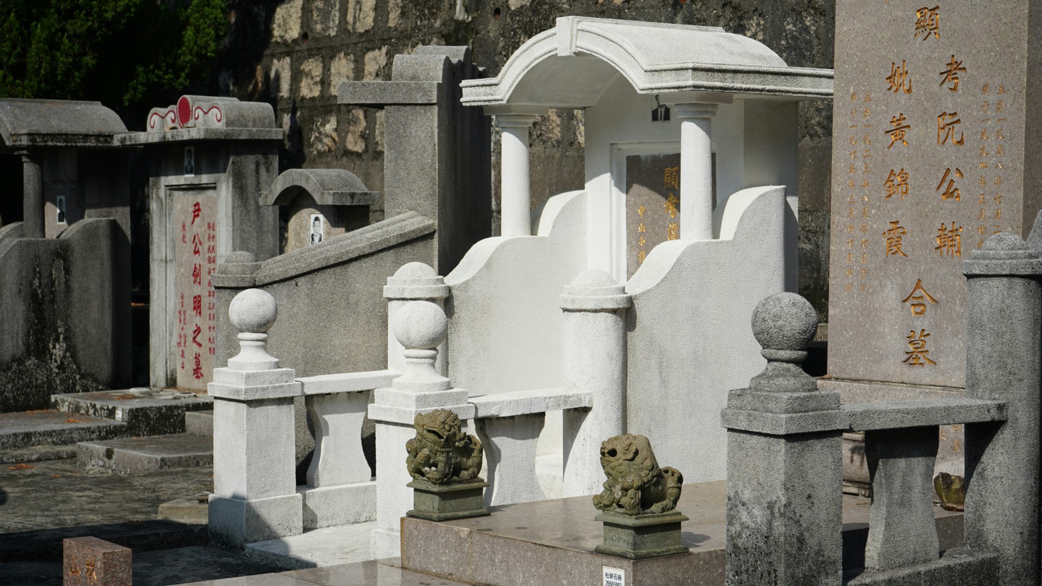 Ornate Chinese tomb with stone guardian lions and gold-lettered inscriptions in a traditional cemetery
