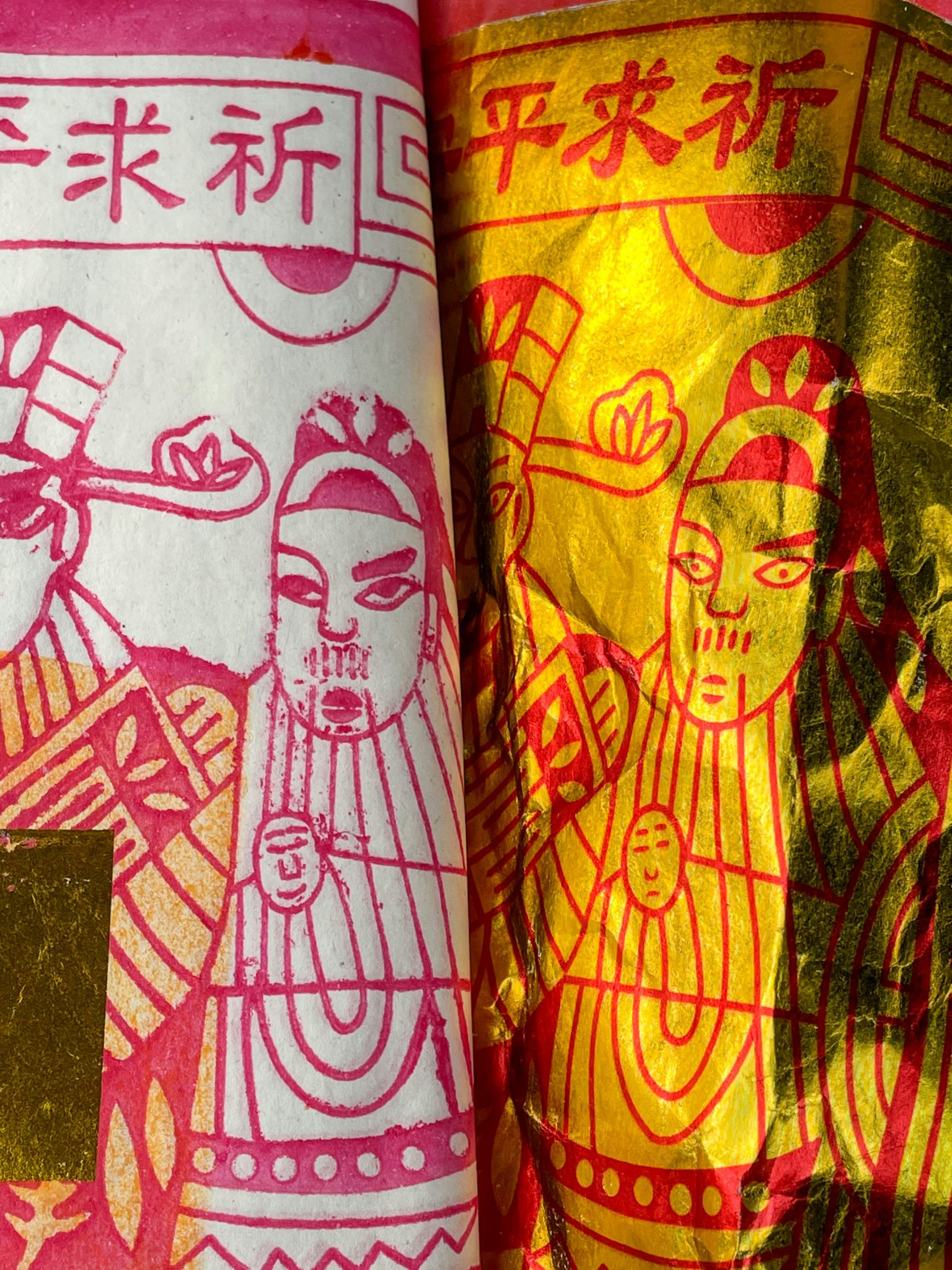 Close-up of two rolls of joss paper — one silver and one gold — printed with deity figures and the characters 祈求平安