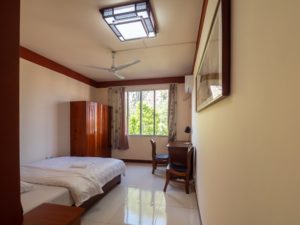 A tidy student bedroom with a bed, wardrobe and ceiling fan