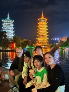 A group poses at night in front of the lit Sun and Moon Pagodas