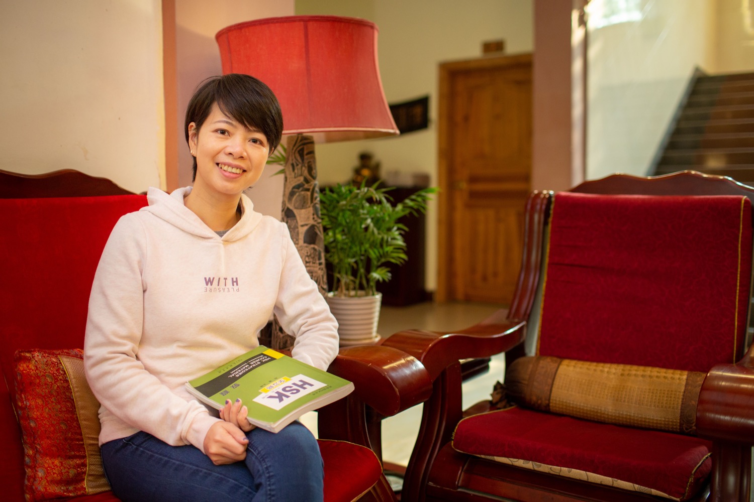 CLI teacher holding an HSK textbook for online test preparation