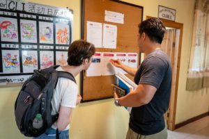 Students read the activities board on a hallway wall