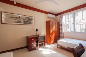 A bright student room with a bed, desk, wardrobe and landscape painting