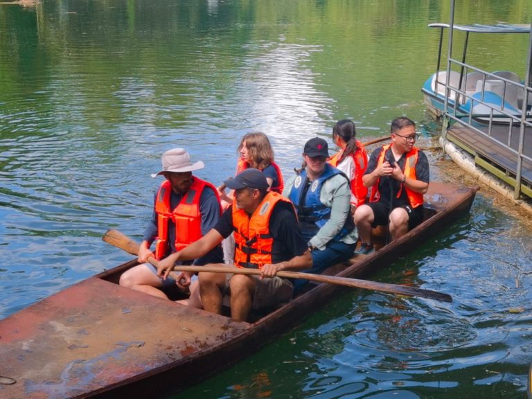 Un groupe en gilets de sauvetage sur un bateau en bois sur une rivière