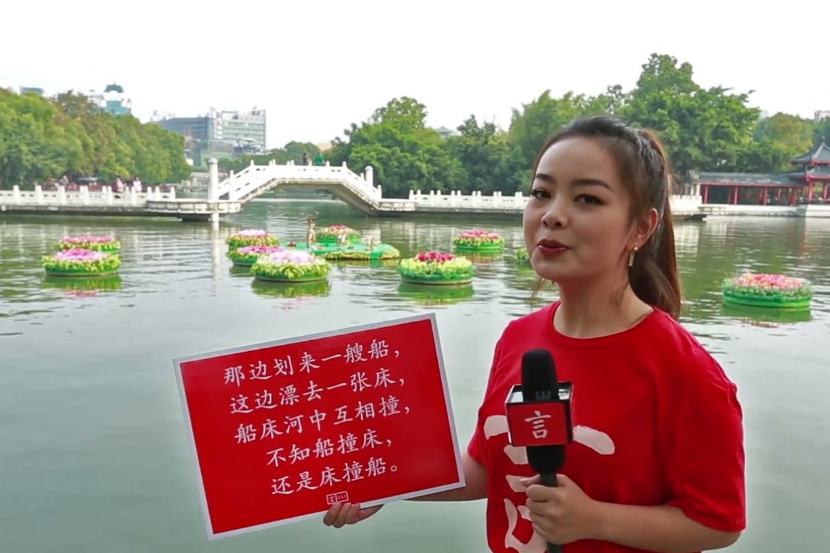 Преподаватель CLI Zicong 老师 держит табличку со скороговоркой 船和床 на берегу озера Жунху в Гуйлине