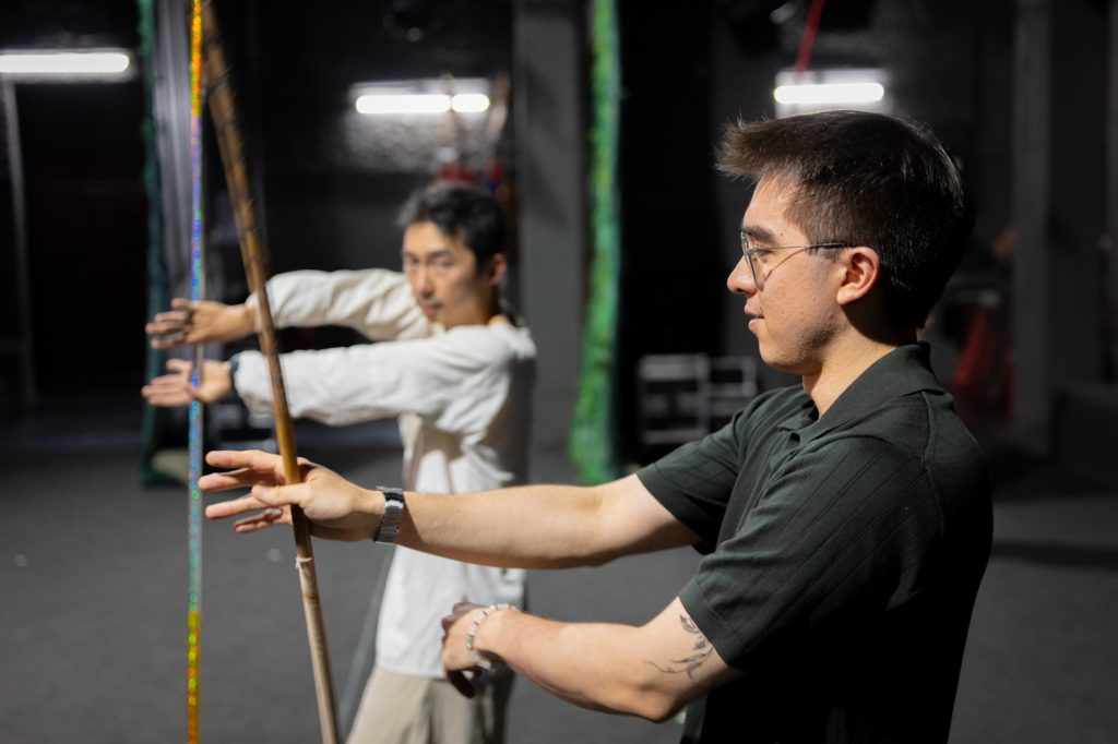 A performer shows a CLI student the basic stance with an opera spear