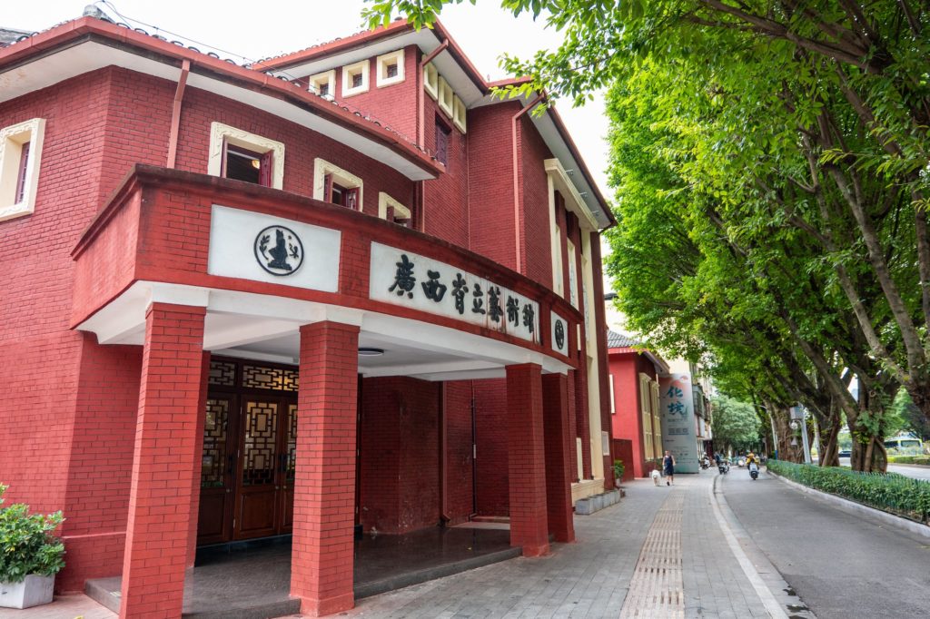 The red brick former Guangxi Provincial Art Hall on a tree-lined street in Guilin